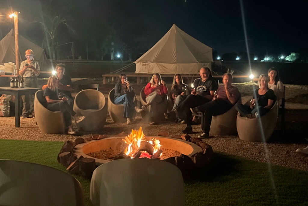 Equipo de trabajo reunido por la noche alrededor de un fogón en un evento corporativo en Terranova Glamping.